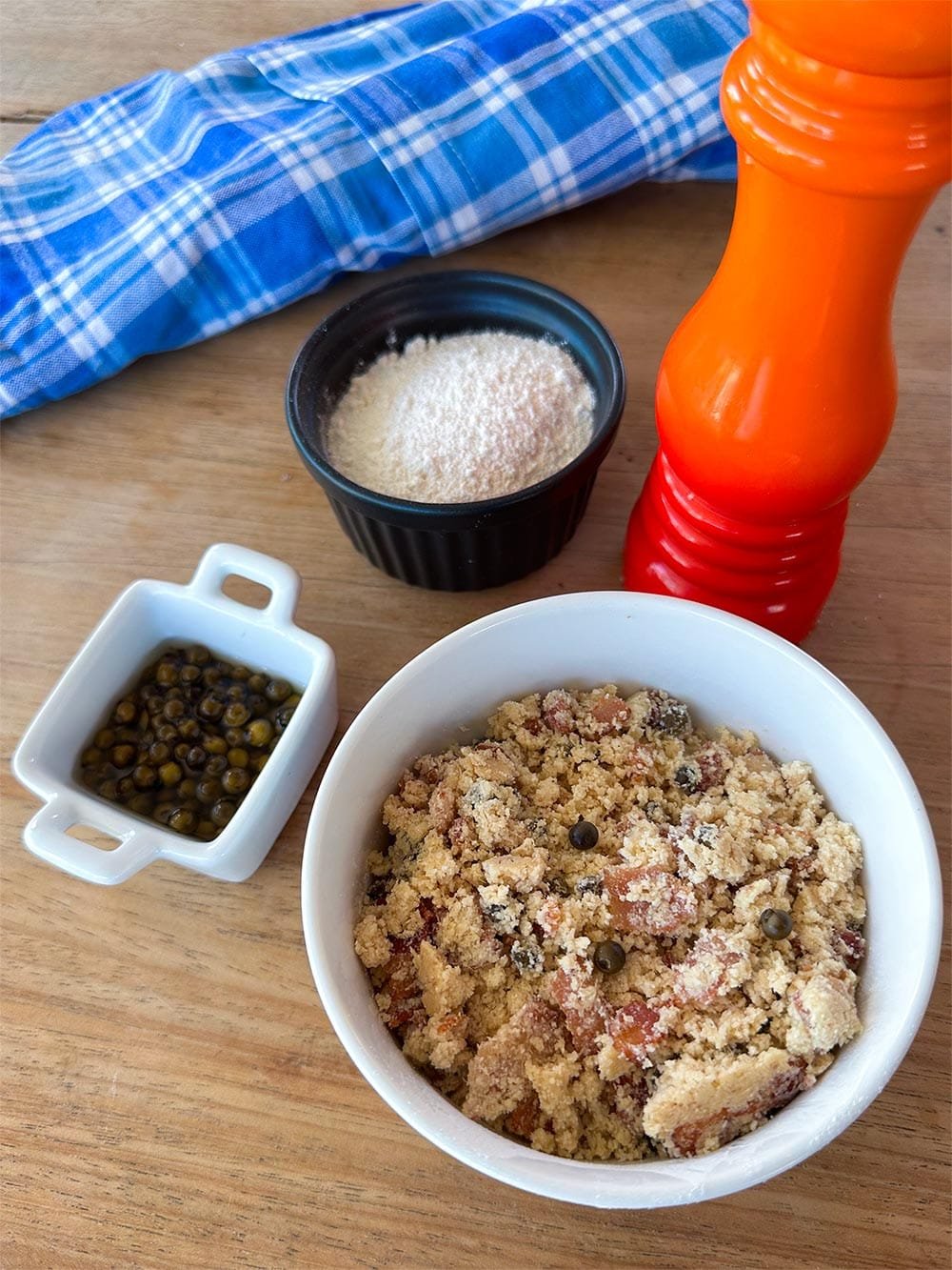 Farofa de bacon com pimenta verde em tigela branca com ingredientes ao redor